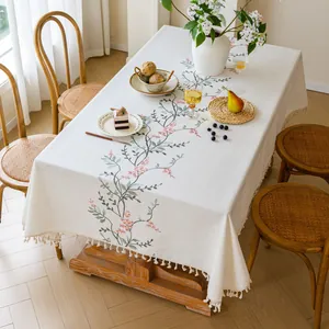 Detailed view of cream embroidered floral tablecloth with elegant tassel fringe edges