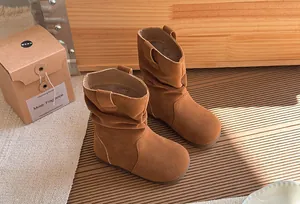 Gros plan sur des bottines plissées marron en daim pour filles au fini rétro élégant