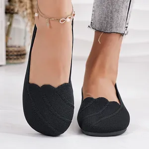Macro detail of black breathable fly-knit round-toe slip-on flat shoes on model feet