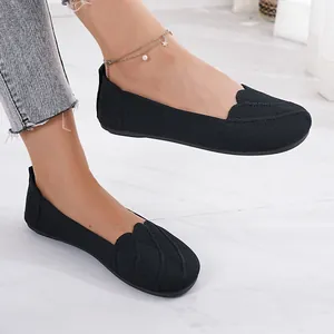 Macro view of women's breathable black flyknit flat shoes with stylish wavy texture