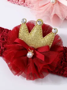 Close-up view of baby headband featuring golden glitter crown and red lace bow detail