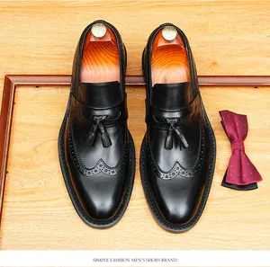 High-quality black leather tassel loafers displayed with wooden shoe trees on a wooden surface