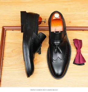 Close-up detail of men's black genuine leather tassel loafers featuring wingtip brogue patterns.