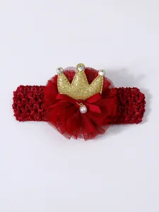 Detailed macro view of red tulle flower and sparkly gold crown on baby crochet headband