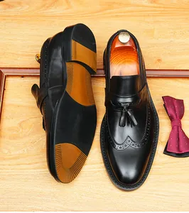 Close-up of black leather tassel loafers showing classic brogue detailing and textured sole.