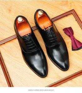Overhead view of black leather Oxford shoes with wooden shoe trees and bow tie detail