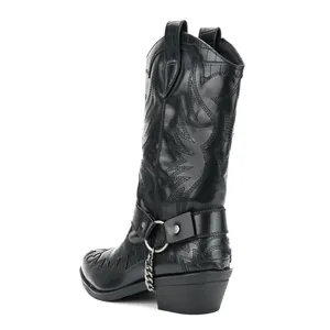 Detailed view of black crocodile pattern cowboy boots with metal chain decoration