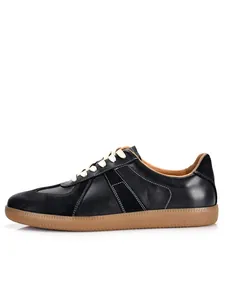 Detailed side view of black leather GAT sneakers with white stitching and gum soles