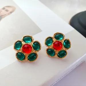 Vue détaillée des boucles d'oreilles fleurs vintage avec gemmes rouges et vertes, fini or.