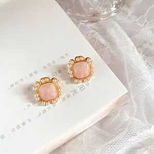 Close-up of elegant French vintage pink enamel earrings with pearl border on a white book