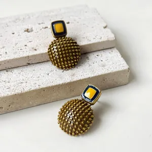 Primer plano de pendientes geométricos de esmalte vintage con textura de puntos dorados