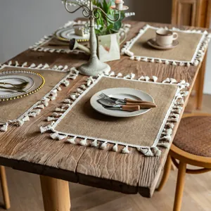 Farmhouse style jute placemats with white tassels on a vintage wooden dining table