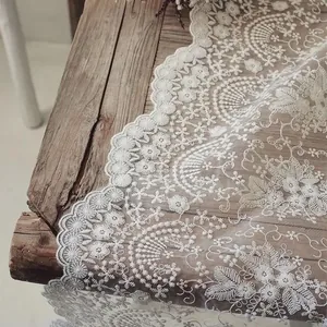 Primer plano de camino de mesa de encaje blanco bordado con intrincados patrones 3D.
