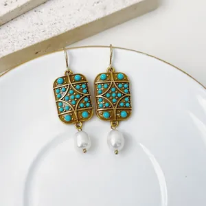 Dettaglio ravvicinato di orecchini geometrici in stile corte vintage con turchese e perle