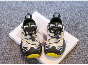 Macro view of breathable mesh and bungee lace system on black and yellow kids' sneakers.