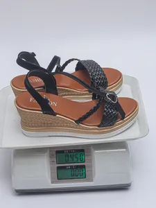 Sandales à talons compensés noirs avec brides tressées pesant 0,450 kg sur une balance