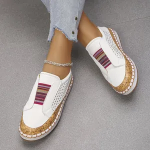 Primer plano de zapatos planos blancos perforados con banda arcoíris y base de corcho