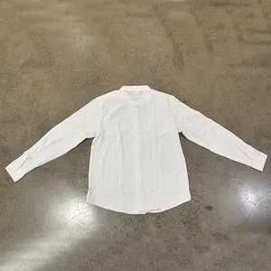 Detailed back view of a classic white long-sleeved linen shirt laid on a gray floor