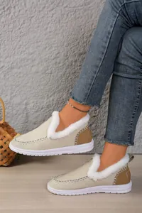 Detailed macro view of beige fur-lined winter loafers with cozy white faux fur trim.