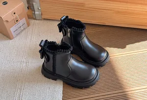 Close-up detail of black British style children's boots with a bow and scalloped trim