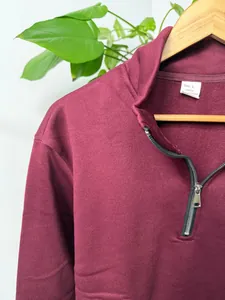 Gedetailleerd aanzicht van de ritskraag van een bordeauxrode fleece herensweater