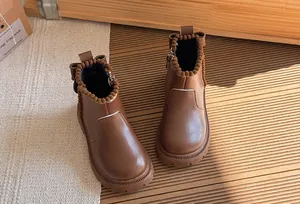 High-angle view of brown girls' British style Martin boots with cute pom-pom trim