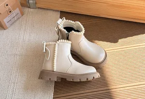 Close-up of girls' beige leather ankle boots featuring pearl trim and sweet back bow detail