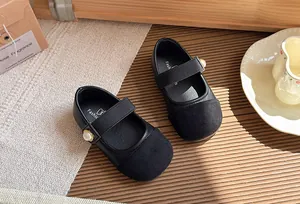 Detailed view of black French style girls' Mary Jane shoes with pearl button strap