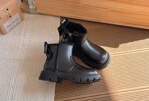 Elegant black girls' Martin boots featuring pom-pom trim and durable lug soles