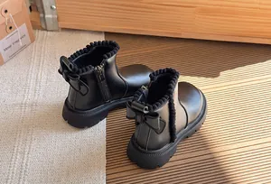 Detail view of black girls Martin boots with bow and plush trim in a cozy setting