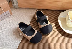 Close-up detail of stylish beige and black Mary Jane shoes for girls with pearl decor