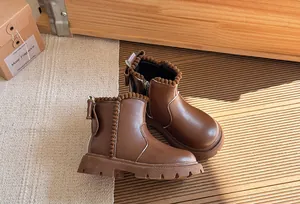 Close-up view of stylish brown children's leather Martin boots with pom-pom and bow details