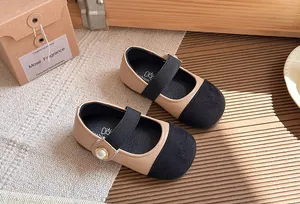Close-up detail of beige and black Mary Jane shoes for girls featuring a pearl button
