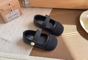 Detailed view of girl's black Mary Jane shoes with suede toe and pearl strap