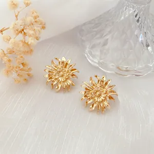 Nahaufnahme von goldenen Barock-Chrysanthemen-Ohrsteckern auf weißem, strukturiertem Stoff
