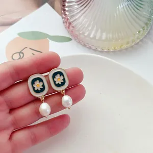 Vue détaillée de boucles d'oreilles vintage en émail fleuri avec perles baroques