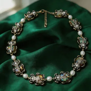 Vista dettagliata di una collana vintage con scarabeo e perle su tessuto in seta verde