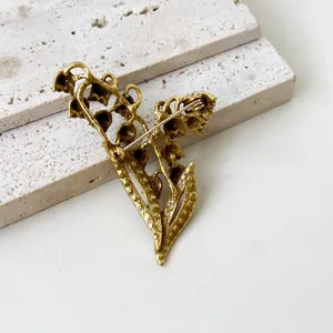 Detailed macro view showing the secure pin mechanism on the back of the vintage lily brooch