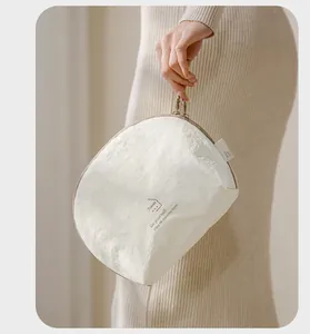 Detail view of a white Taslan packing cube with Travel print held by an elegant model