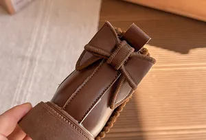 Detail view of brown girls' Martin boots featuring a stylish bow and warm plush lining