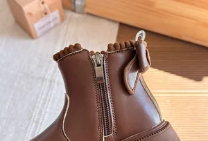 Detail of brown children's ankle boots with side zipper and decorative bow