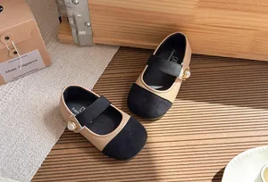 Close-up of elegant girl's Mary Jane shoes with pearl detail and beige black patchwork
