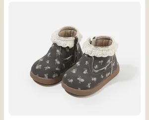 Nahaufnahme des zarten Blumenmusters und des Spitzenbesatzes dieser Kleinkindstiefel für Mädchen