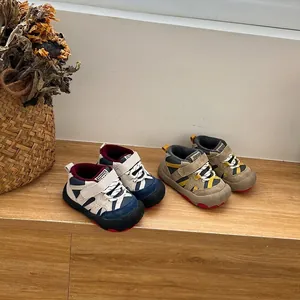 Detailed view of children's fleece-lined sports shoes in blue and khaki on a wooden shelf.