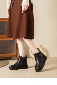 Detailed view of black leather ankle boots with fur lining and soft soles on model