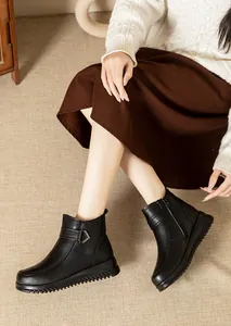 Detailed view of black winter ankle boots with side zipper and buckle worn by a model