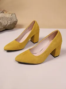 Primo piano di décolleté in camoscio giallo con tacco largo e punta elegante