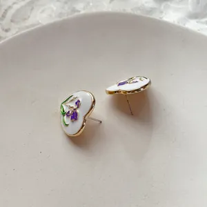 Dettaglio degli orecchini a cuore vintage con smalto iris viola e bordo dorato.
