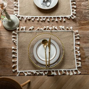 Rustic jute placemat with white tassel trim shown on a wooden farmhouse table