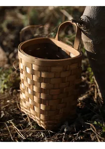 Vue détaillée d'un panier suspendu en bois tressé rustique dans un cadre naturel extérieur